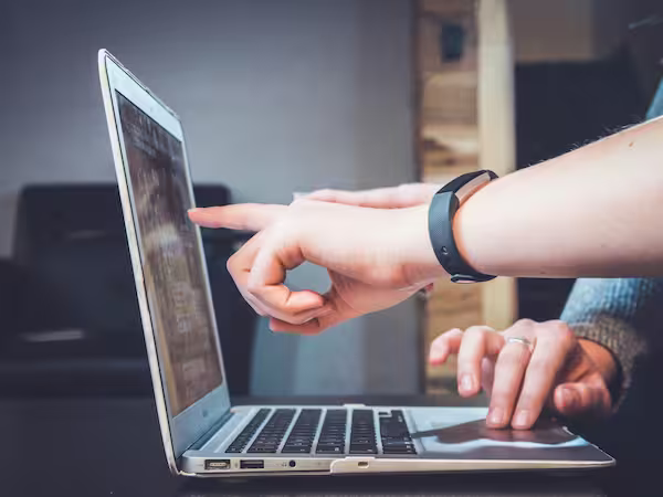 A hand pointing at a laptop screen